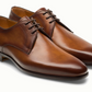 The Magnanni Maddin Lace-Up shoes are brown calfskin plain toe derbies with laces, a low heel, and smooth finish from the Línea Flex collection, shown side by side on a white background.