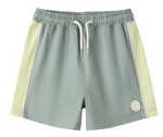 The Rylee & Cru Baby Boys' and Boys' Paneled Boardshort features light green fabric with off-white side panels, a white drawstring, elastic waistband, and a logo patch. Made with UPF 50+ fabric for added sun protection.