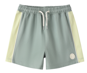 The Rylee & Cru Baby Boys' and Boys' Paneled Boardshort features light green fabric with off-white side panels, a white drawstring, elastic waistband, and a logo patch. Made with UPF 50+ fabric for added sun protection.