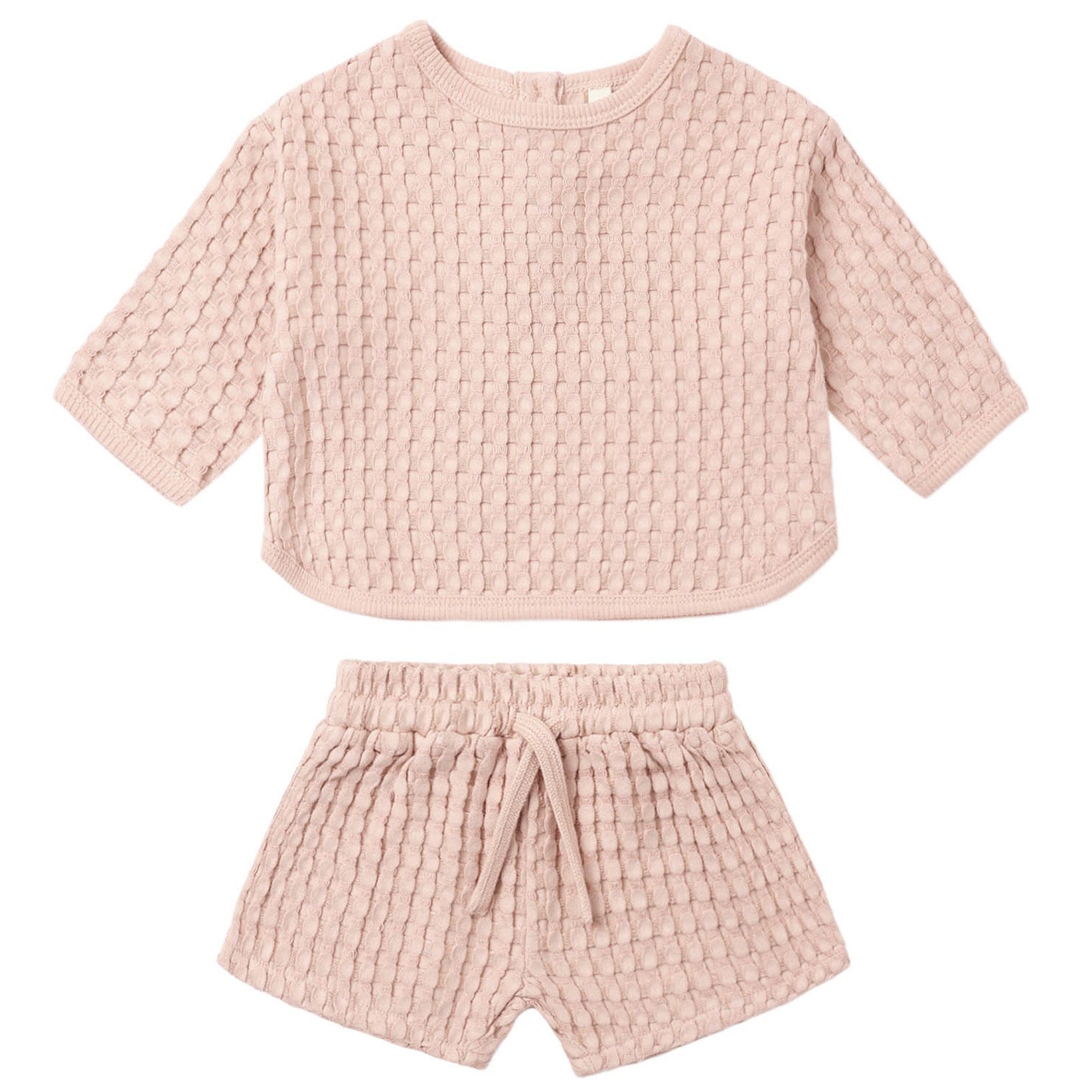 The Quincy Mae Baby Girls’ and Girls’ Flynn Set features a light pink, short-sleeve top and matching shorts in a cozy waffle knit, complete with a drawstring waistband—perfect for comfortable everyday wear.