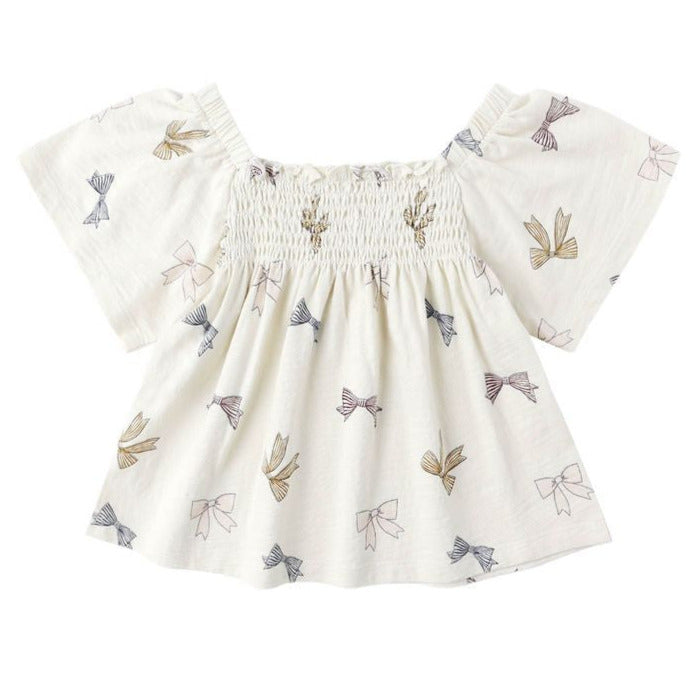 The Baby Girls' and Girls' Kate Top by Rylee & Cru features a smocked neckline and charming bows, bringing a sweet touch to this classic white top.