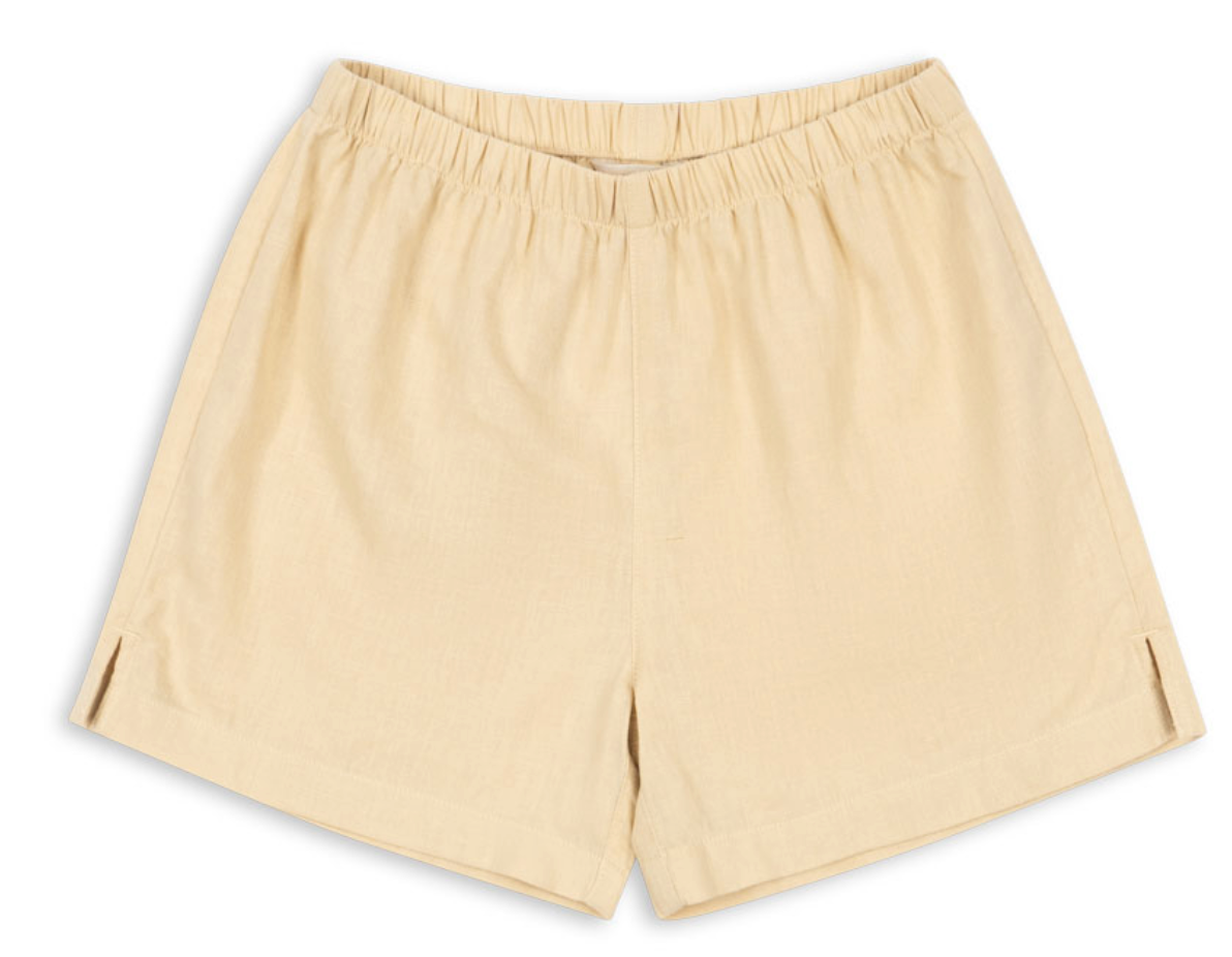 Introducing the Konges Slojd Baby Boys’ and Boys’ Franzen Linen Shorts, crafted from a comfortable linen blend in a beige hue. These knee-length shorts feature an elastic waistband and subtle side slits at the hem, shown laid flat on a white background.