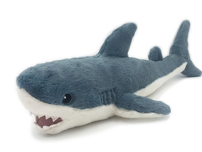 Meet the Seaborn Shark from Mon Ami—a plush toy with blue and white fur, black eyes, and visible white teeth, lying on a white surface. This adorable cuddle buddy is perfect for snuggling at bedtime or playtime alike.