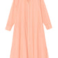 The Xirena Boden Dress is a peach, long-sleeve, button-front shirtdress with a collar and side slits, made from woven cotton poplin, shown on a white background.