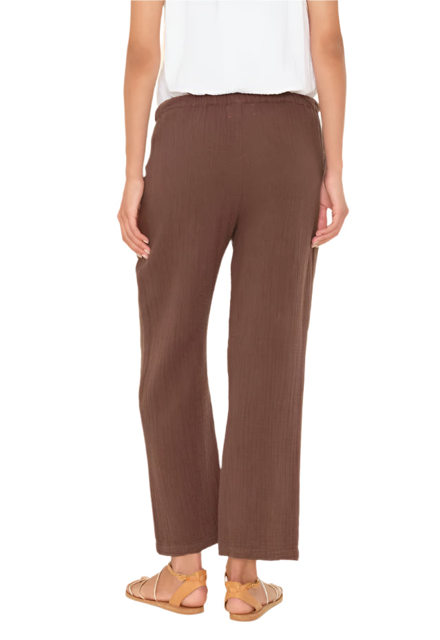 A person is shown from the back wearing a white top, tan sandals, and Xirena's Ozzie Pant—a cropped pull-on style with an elasticized drawstring waist.