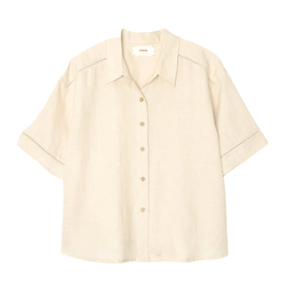 The Xirena Hendry Shirt is a beige, short-sleeved linen button-up with coconut buttons and a collar, shown on a plain white background.
