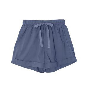 The Declan Short by Xirena is a light blue, lightweight woven cotton short with an elastic drawstring waist, side seam pockets, and folded hems, shown laid flat on a white background.