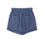 The Declan Short by Xirena is made from lightweight blue woven cotton with an elastic waistband, side seam pockets, and rolled cuffs, shown on a white background.