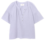 The Nia Top by Xirena is a light purple cotton gauze popover with short flutter sleeves, a round collar, button placket, and loose-fitting textured fabric.
