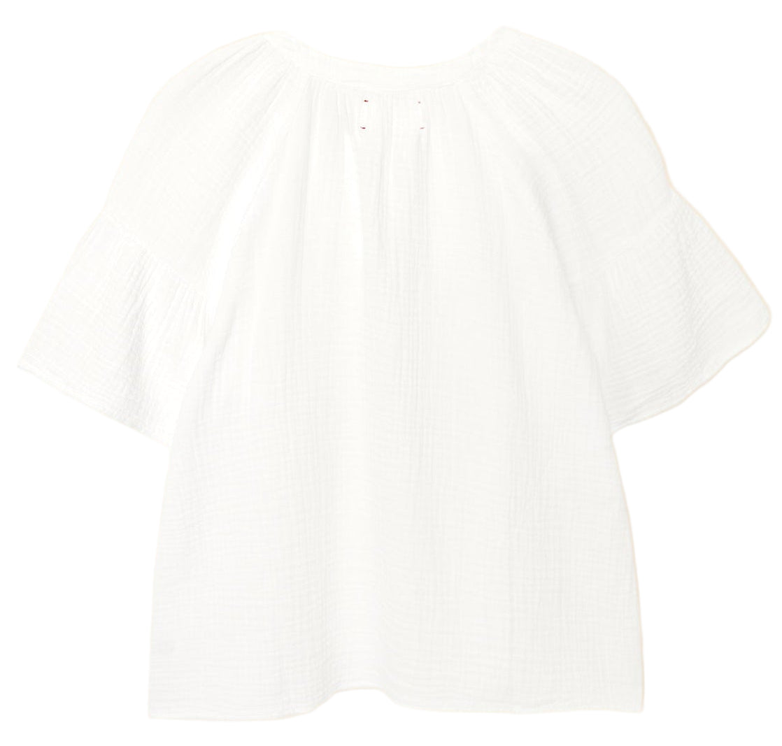 The Nia Top by Xirena is a loose-fitting white cotton gauze popover featuring short flutter sleeves, a round neckline, and gathered detailing.