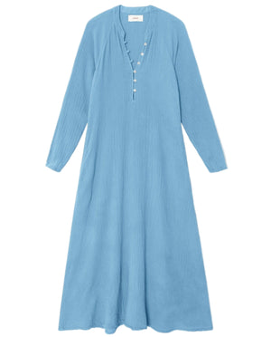 The Xirena Tabitha Dress is a light blue cotton gauze midi with long raglan sleeves, a buttoned placket, and a flowy, loose fit, shown on a white background.