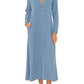 A woman wearing the Xirena Tabitha Dress, a light blue, long-sleeve cotton gauze dress with a buttoned neckline, and brown flat shoes.
