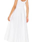 A woman, back turned against a white background, wears the Xirena Florence Dress—a sleeveless midi sundress with a smocked bodice and square neck—paired with tan sandals.