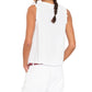 A woman with a braid is shown from the back wearing the Xirena Portia Top, a sleeveless white cotton gauze piece, paired with white pants and her left hand in her pocket.