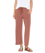 Person wearing a white t-shirt, Xirena Matteo Sweatpant in vintage washed French terry, and brown embellished sandals, standing with hands in pockets.