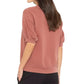 A woman wearing the Xirena Jax Sweatshirt, a vintage washed French terry short-sleeve top, and black pants stands with her back to the camera against a white background.