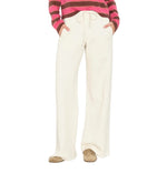 Wearing the Xirena Renzo Sweatpant—a cream-colored, wide-leg style with an elasticized drawstring waist—paired with tan shoes and a pink and brown striped long-sleeve shirt, hands in pockets, photographed from shoulders down.