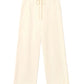 The Renzo Sweatpant by Xirena is a pair of wide-leg cream pants crafted from ultra-soft fleece, featuring an elasticized drawstring waist and side pockets, shown laid flat on a white background.