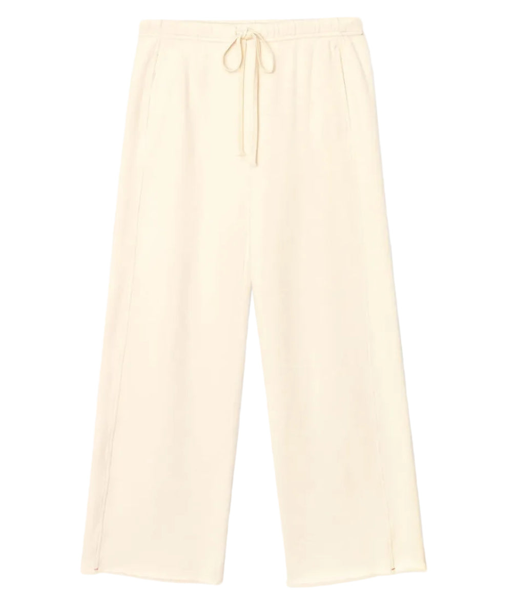 The Renzo Sweatpant by Xirena is a pair of wide-leg cream pants crafted from ultra-soft fleece, featuring an elasticized drawstring waist and side pockets, shown laid flat on a white background.