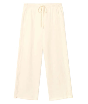 The Renzo Sweatpant by Xirena is a pair of wide-leg cream pants crafted from ultra-soft fleece, featuring an elasticized drawstring waist and side pockets, shown laid flat on a white background.