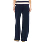 A person wearing the Xirena Renzo Sweatpant in navy blue, featuring a wide-leg silhouette and an elasticized drawstring waist, paired with a short-sleeved striped top; photographed from the back against a white background.