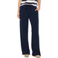 A person wearing the Xirena Renzo Sweatpant in navy with an elasticized drawstring waist, styled with a striped short-sleeve top and beige shoes, photographed from the shoulders down against a white background.