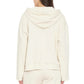 A person is seen from the back wearing the Xirena Chase Sweatshirt in a cream shade, featuring a relaxed fit, kangaroo pocket, and paired with matching pants. The ultra-soft fleece fabric enhances comfort against the plain white background.
