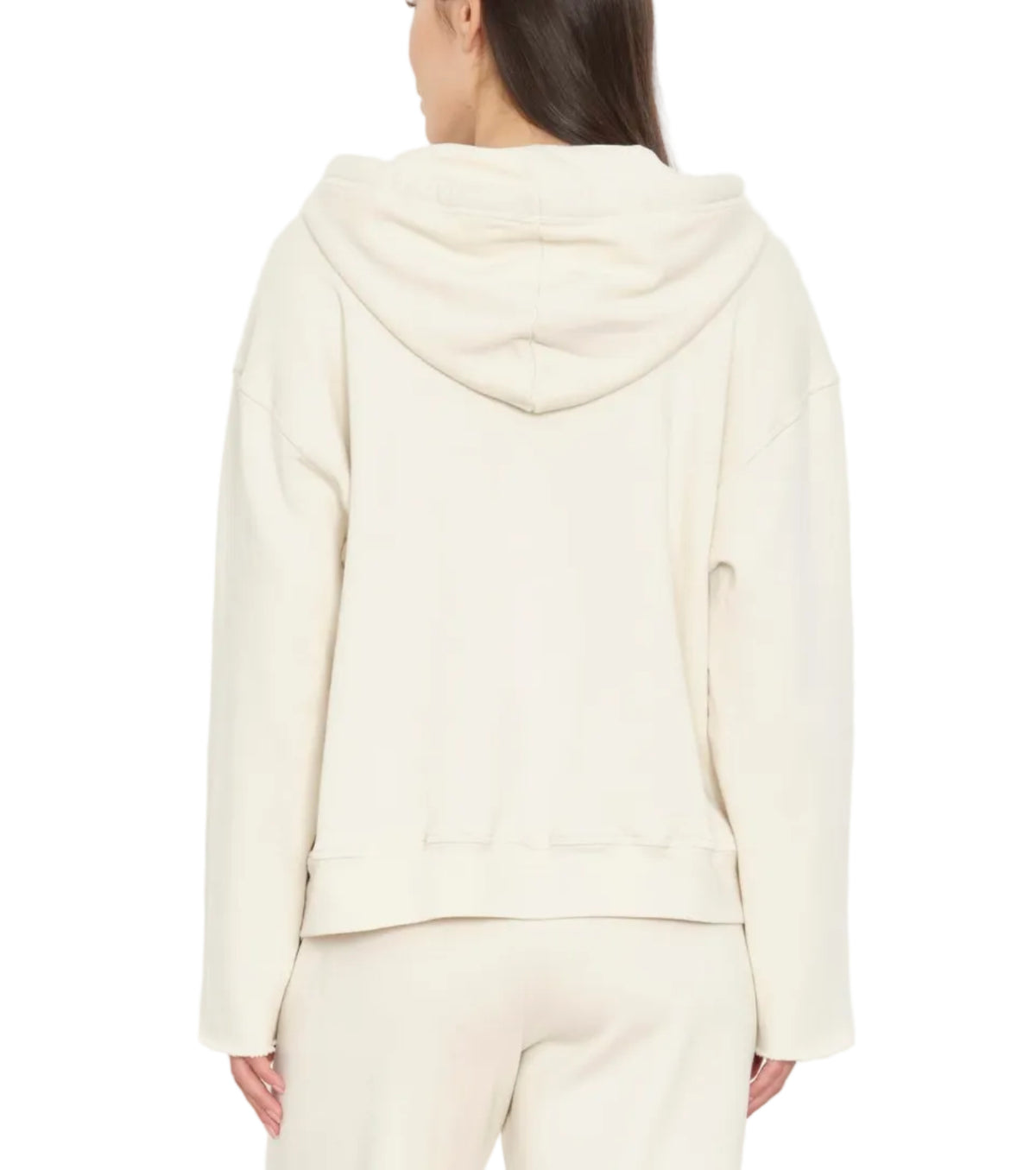 A person is seen from the back wearing the Xirena Chase Sweatshirt in a cream shade, featuring a relaxed fit, kangaroo pocket, and paired with matching pants. The ultra-soft fleece fabric enhances comfort against the plain white background.