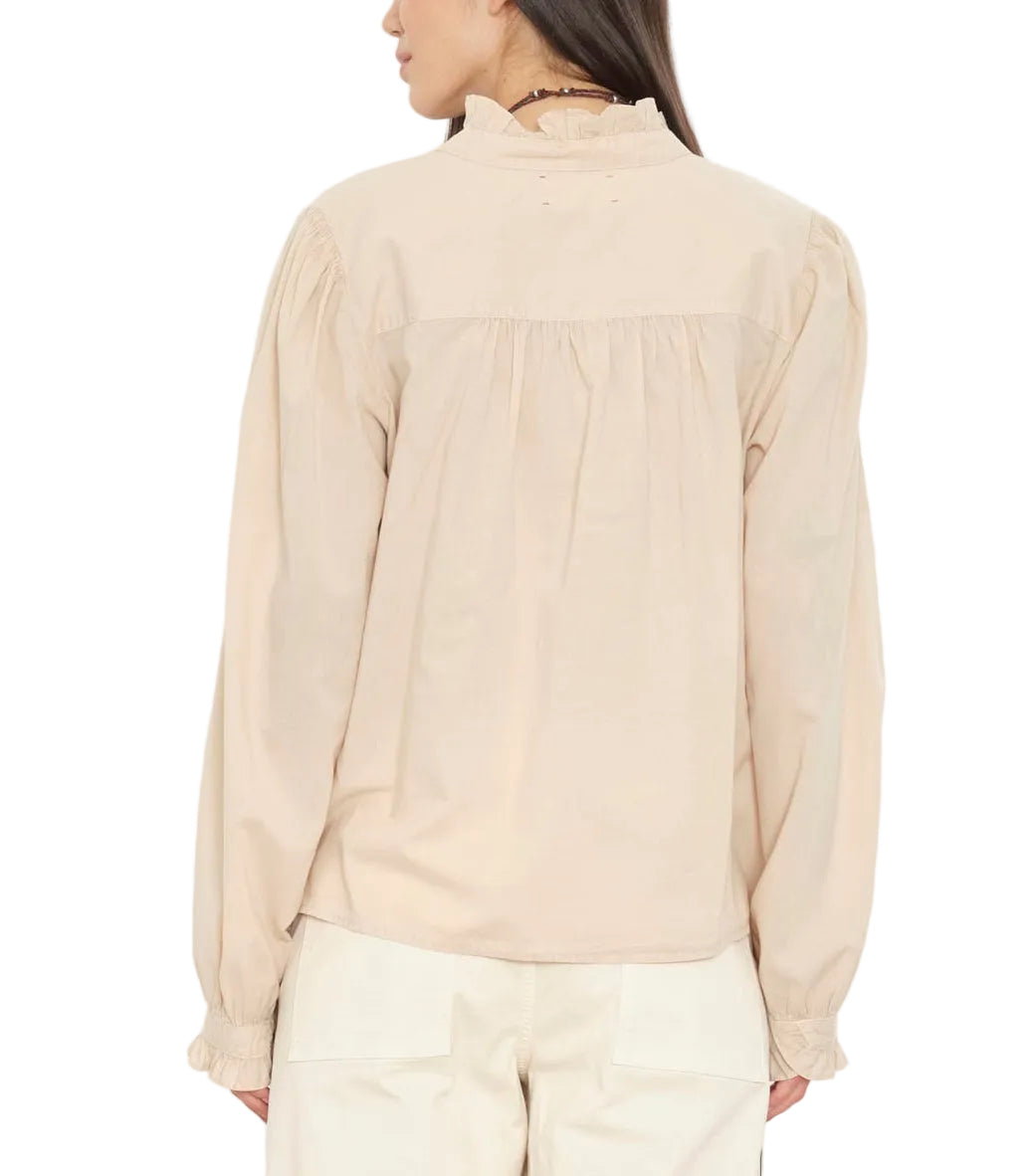 A person shown from the back wearing the Dorien Top by Xirena, a long-sleeve beige blouse featuring blouson sleeves and a ruffled collar, paired with cream pants.