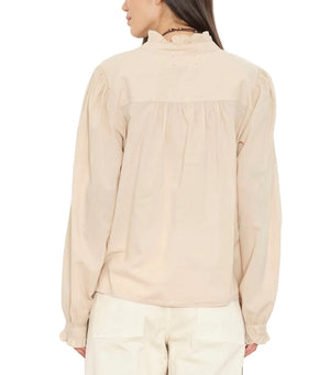 A person shown from the back wearing the Dorien Top by Xirena, a long-sleeve beige blouse featuring blouson sleeves and a ruffled collar, paired with cream pants.