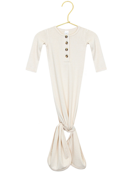 The Lou Lou & Company Baby Dakota Plush Knit Knotted Gown features a cream color, long sleeves, a button-down front, and a convenient knotted tie bottom for hassle-free diaper changes. It is displayed on a gold hanger against a white background.