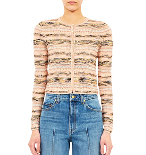 A person wearing the Ulla Johnson Mia Knit Cardigan—a long-sleeve patterned button-up in pastel tones—paired with blue high-waisted jeans.