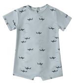 The Rylee & Cru Baby Boys' Shorty One-Piece features light blue fabric with dark shark silhouettes, small waves, and UPF 50+ protection—perfect for sunny adventures.