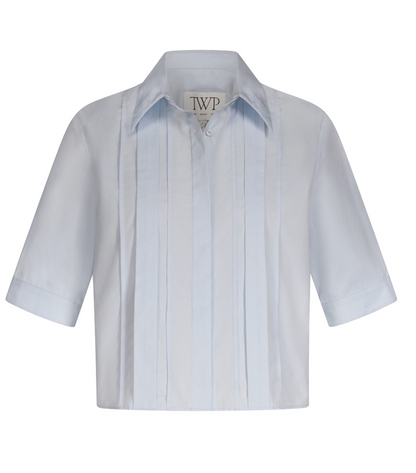 The Short Lived Cherry Pleat Top by TWP is a light blue cropped button-down shirt with a collar and vertical pintuck detailing, shown against a plain white background.