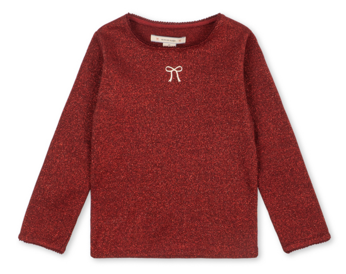 Girls’ Roli Blouse by Konges Slojd, a long-sleeved, glittery red knitted top with a small white bow detail at the neckline.