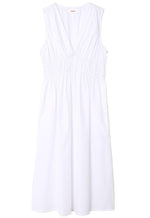 The Xirena Cyra Dress in white cotton poplin features a V-neck and gathered details at the waist, displayed on a pristine white background.