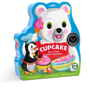Colorful box of Eeboo’s "Cupcake Shaped Spinner Game" featuring a cartoon polar bear holding a cupcake and a penguin in a chef hat, with text inviting players to gather ingredients and follow play instructions for this delightful spinner game—perfect for family fun and imaginative pretend play.