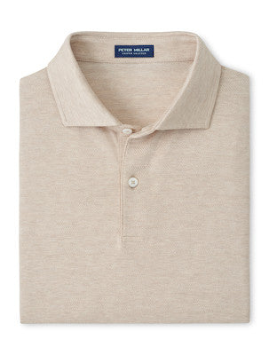 A folded beige short-sleeve Excursionist Flex Herringbone Knit Polo by Peter Millar with a collar and two buttons, featuring the brand’s label on the inside neck and crafted from soft cotton jersey knit.