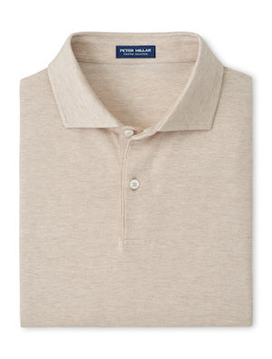 A folded beige short-sleeve Excursionist Flex Herringbone Knit Polo by Peter Millar with a collar and two buttons, featuring the brand’s label on the inside neck and crafted from soft cotton jersey knit.