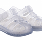 The Igor Girls' Star Jelly Sandal features translucent, glittery PVC, closed toes, adjustable straps, and a removable foot bed for comfort.