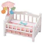 The Calico Critters Crib with Mobile is a small white and pink toy crib featuring a pink mattress, blue bow, three bottom drawers, and a pastel mobile attached to one corner—ideal as dollhouse furniture or as part of a baby nursery set.