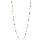 The Gigi Clozeau Side Cross Necklace 16.5" features a timeless design with a sideways cross pendant, turquoise beads, and accents of resin pearls elegantly arranged along an 18 carat gold chain.