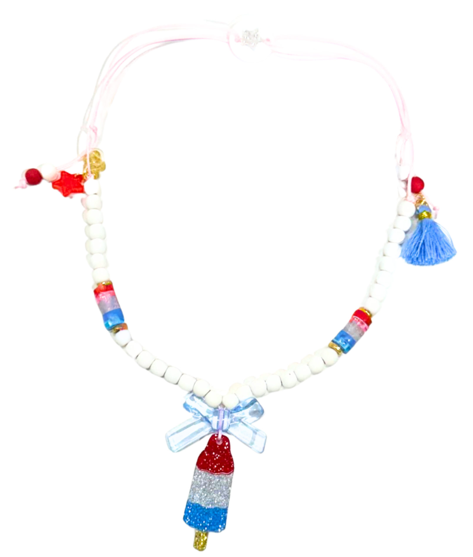 Add a playful touch to any outfit with the Lillies & Roses Popsicle Rocket Red White Blue Necklace, featuring white beads, red and blue accents, a blue tassel, bow, star charm, and a glittery rocket popsicle pendant.
