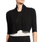 A woman wears the Lela Rose Scallop Trim Knit Bolero over a black and white knit dress with vertical perforated patterns.