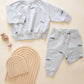 A light grey Quincy Mae Baby Boys' and Boys' Relaxed Fleece Sweatshirt set with whale prints, shown with wooden stacking arches and a rattle on a cream background—a cozy must-have for your toddler.