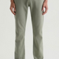 A person wearing the Everett Slim Straight jeans by AG Jeans in light green, featuring a mid-rise waist, paired with a grey shirt tucked in and beige sneakers, stands against a plain white background.