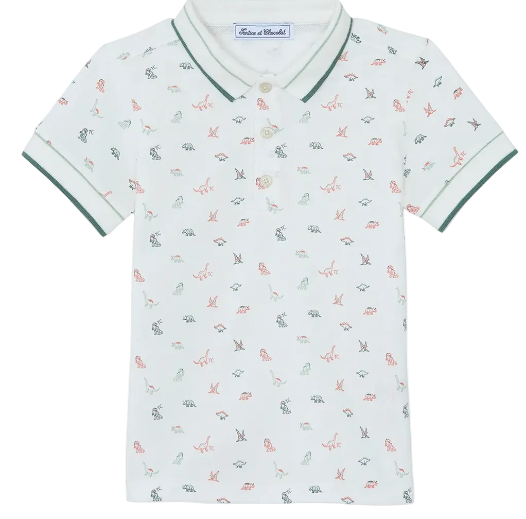 Introducing the Boys’ Polo Shirt by Tartine et Chocolat: a short-sleeved white polo for kids, adorned with a subtle dinosaur pattern, finished with contrasting green trim on the collar and sleeves, and featuring a classic three-button placket.