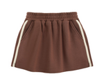 The Girls’ Sports Skirt by Rylee & Cru, featuring an elastic waistband, side pockets, and white vertical stripes along the sides, is laid flat on a white background.
