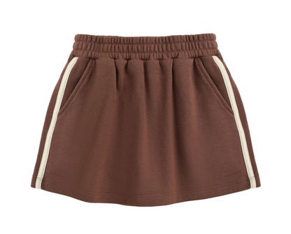 The Girls’ Sports Skirt by Rylee & Cru, featuring an elastic waistband, side pockets, and white vertical stripes along the sides, is laid flat on a white background.