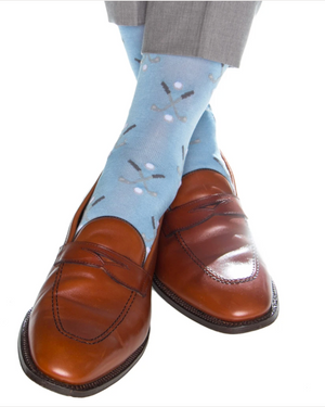 A person wears Dapper Classics Sky Blue with Steel Golf Club and Ball cotton socks with brown leather loafers and light grey pants.